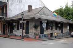 an old wooden building with a rainbow flag on the roof and two cars parked in front