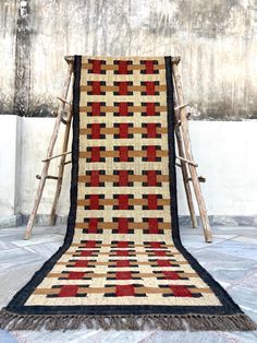 an old rug is sitting on the floor next to a wooden chair with a blanket over it