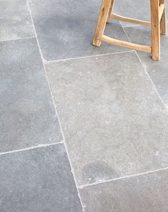 a wooden stool sitting on top of a stone floor