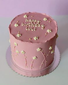 a pink birthday cake with white flowers on it