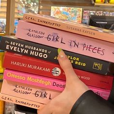 a person holding a stack of books in front of a store display case filled with children's books