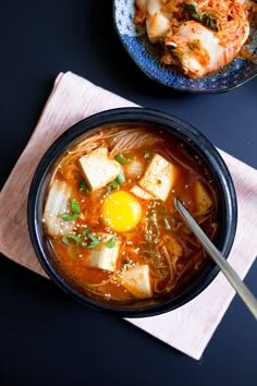 two bowls of soup with tofu, noodles and an egg on the top one