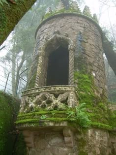 an old stone tower with moss growing on it's sides in the foggy forest