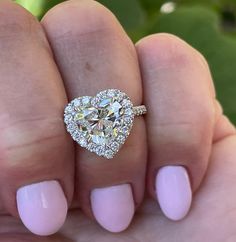 a woman's hand holding a heart shaped diamond ring