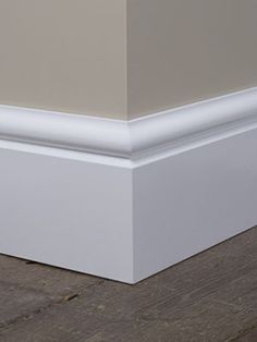 the corner of a room with wood flooring and white paint on the walls is shown