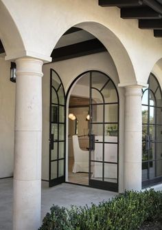 the front entrance to a house with arched windows and glass doors on either side of it