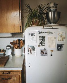 an old refrigerator with magnets and pictures on it in a kitchen next to a potted plant