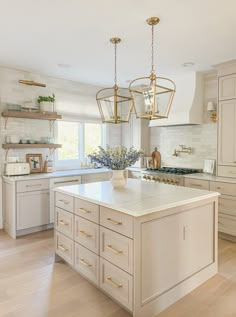 a large kitchen with white cabinets and an island in the middle is decorated with gold accents