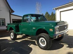 a green truck parked in front of a garage