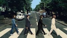 the beatles crossing the street in front of an old white vw bug on a crosswalk