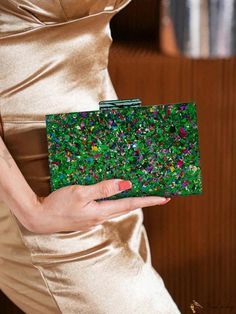 a woman in a gold dress holding a green clutch bag with colorful sprinkles on it