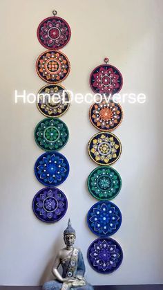 a buddha statue sitting in front of a wall hanging with seven chakras on it