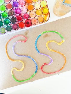 the letters s and s are made out of colored crayons next to some watercolors