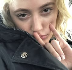 a close up of a person wearing a jacket and pointing to the side with her finger