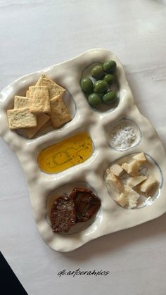 a tray with crackers, olives, cheese and other food items on it