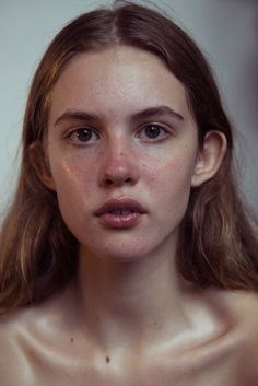 a woman with freckles on her face is looking at the camera while she has long hair