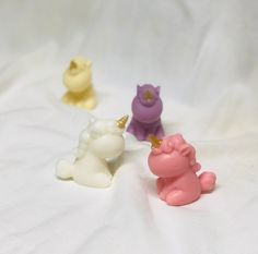 four small plastic unicorn figurines sitting on top of a white sheet