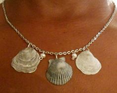 a woman wearing a necklace with three seashells on it