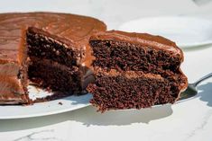 a piece of chocolate cake on a white plate with a slice taken out of it