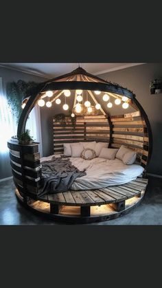 a bed made out of wooden pallets with lights hanging from the top and bottom