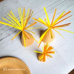 two small vases with yellow sticks sticking out of them sitting on a white surface