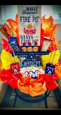 a basket filled with candy and candies on top of a table next to a sign that says what happens fire pit stays at the pur