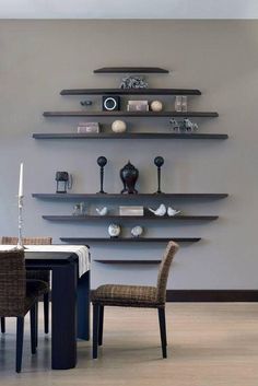 a dining room table with chairs and shelves on the wall