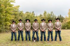 a group of men standing next to each other in front of some trees and grass