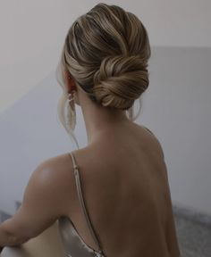 a woman with her hair in a low bun is looking at something on the wall