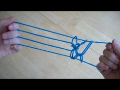 two hands holding blue string with scissors on top of wooden floor next to each other