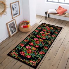 a black rug with red and green flowers on it in a room next to a window