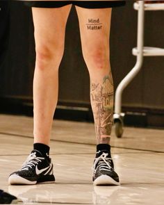 a person with tattoos on their legs standing in front of a basketball ball and net