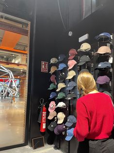 a woman is looking at hats on display