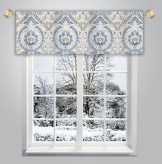 a window with a blue and white valance hanging from it's side, in front of a snowy landscape