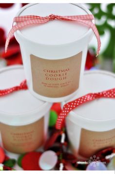 three white cups with red ribbon around them on a table next to other christmas decorations