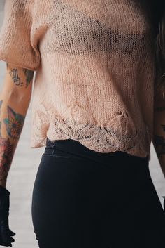 a woman with tattoos wearing black gloves and a pink shirt is walking down the street