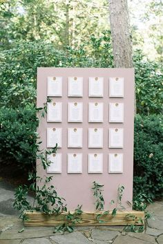 a wedding seating chart with greenery and gold dots is displayed in front of a tree