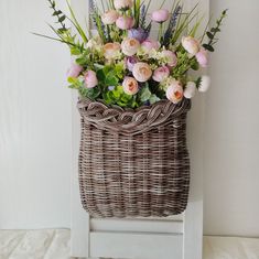 a basket filled with flowers sitting on top of a white chair next to a wall