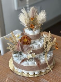 a three tiered diaper cake decorated with flowers and feathers