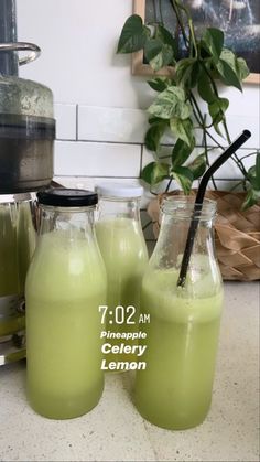 two glass bottles filled with green liquid sitting on top of a counter