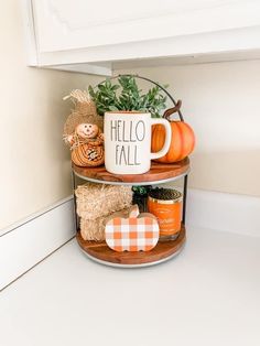 two tiered shelves with pumpkins, hay and coffee mugs on them in the corner of a kitchen