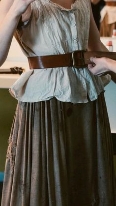 a woman wearing a dress and belt holding something in her hand