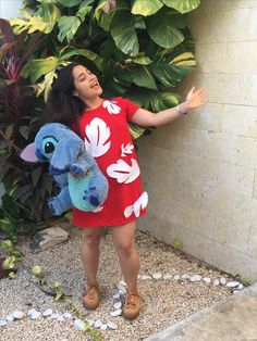 a woman in a red dress holding onto a stuffed animal and smiling at the camera