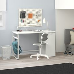 a white desk with a computer on top of it in front of a gray couch