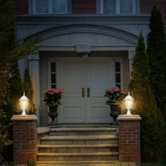 two planters with flowers are sitting on the steps in front of a house at night