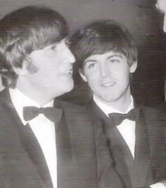 two young men in tuxedos smile at each other