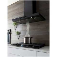 a stove top oven sitting inside of a kitchen next to a wall mounted pot filler