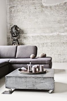 a living room with a gray couch and coffee table in front of a brick wall