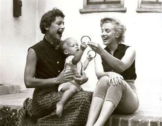 an old photo of two women and a baby on the steps with scissors in their hands