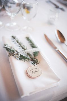 a place setting with silverware and greenery